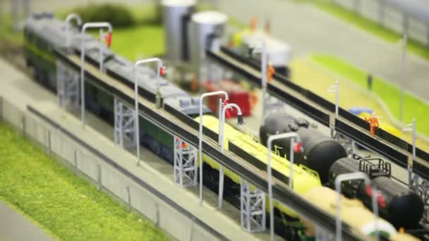Поезд с танком идет по железной дороге от автозаправочной станции в современном игрушечном городе — стоковое видео