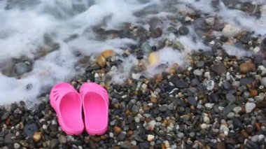 Çocuk pembe terlik çakıl plajı ile deniz üzerinde sörf