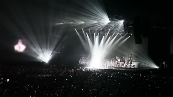 Na sala de concerto olham para o cantor na luz de raios — Vídeo de Stock