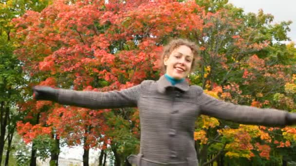 Joven mujer dando la vuelta y lanzando hojas de otoño a la cámara — Vídeos de Stock