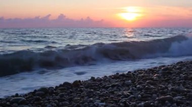 Deniz sörf çakıl plajı, yukarıda arka planda dalgalanan deniz günbatımı gökyüzü
