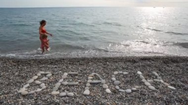 küçük kız deniz Sörfü, plaj yazıt ön planda çalışan kadın