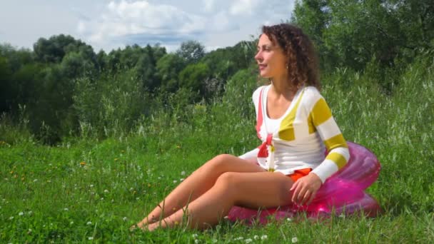 Молодая счастливая красивая женщина сидит на надувном сиденье на открытом воздухе — стоковое видео