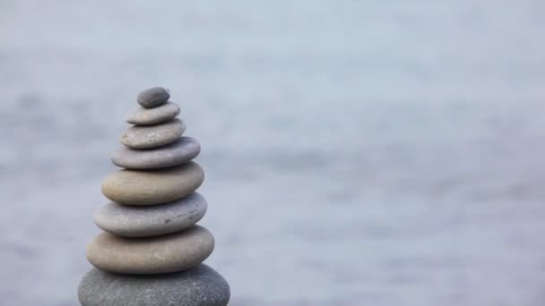 Stone stack on pebble beach, sea in background, vertical panning — Stock Video