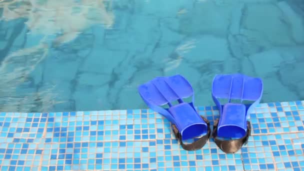 Aletas azules está en el borde de mosaico de la piscina con agua clara — Vídeos de Stock