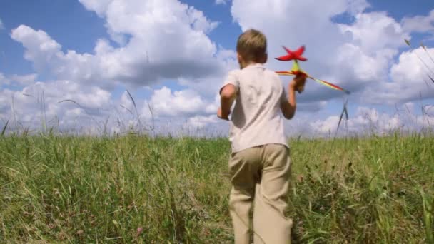 Boy running through the field with airplane — Stock Video