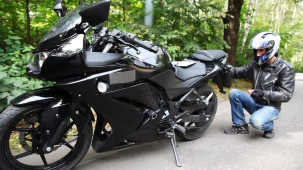 Motocyklista laczy rejestracyjne na czarny motocykl — Wideo stockowe