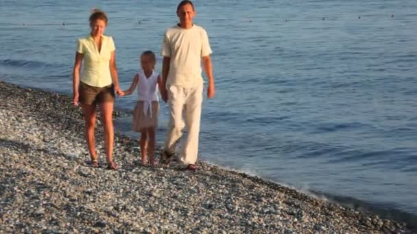 Andando família feliz com a menina na praia de seixos, para a câmera — Vídeo de Stock