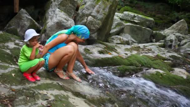 Younf woman and little girl near brook running on rock — Stock Video