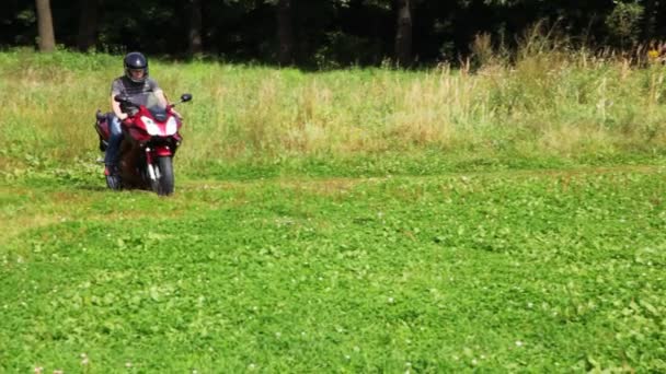 Motociclistas em bicicleta vermelha cruza campo no parque — Vídeo de Stock