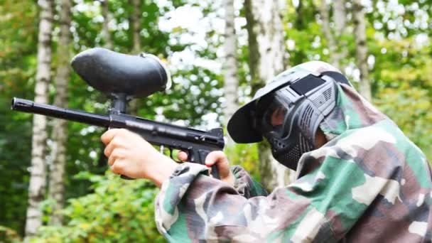 Hombre en casco y máscara con soporte de pistola de paintball y pretende que los objetivos — Vídeos de Stock