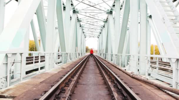 Рудий молодий чоловік йде вперед на камеру на залізничному мосту — стокове відео