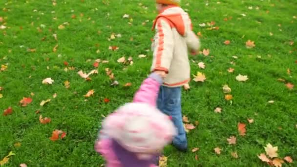 Menino e menina girando no parque de outono, juntar as mãos — Vídeo de Stock