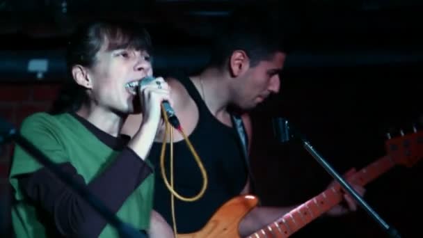 Молодая вокалистка с пением микрофона, гитарист против — стоковое видео