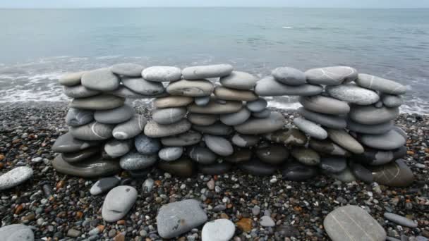 Pared de piedras en la playa, el mar de surf en el fondo — Vídeos de Stock