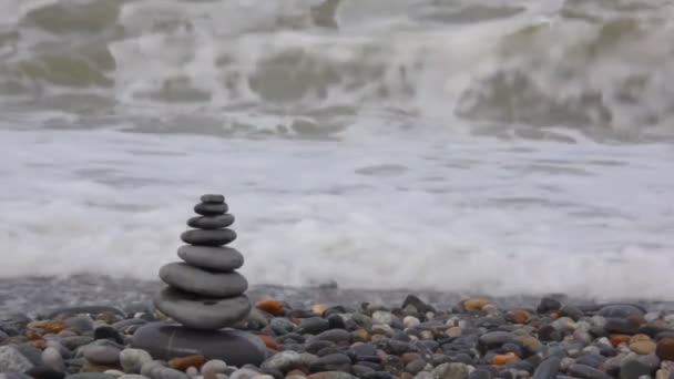 Pila de piedra en la playa de guijarros, agitando el mar en el fondo — Vídeos de Stock