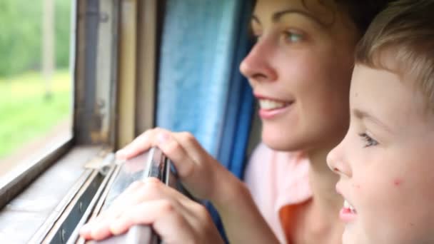 Joven mujer y niño mirando a la naturaleza desde el transporte ferroviario en movimiento — Vídeo de stock