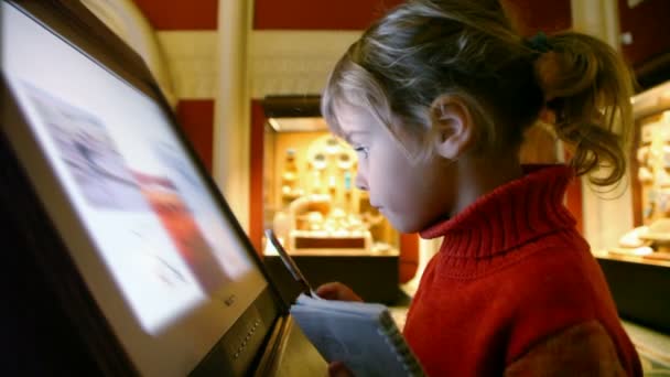 Маленькая девочка смотрит интерактивную экспозицию в музее — стоковое видео