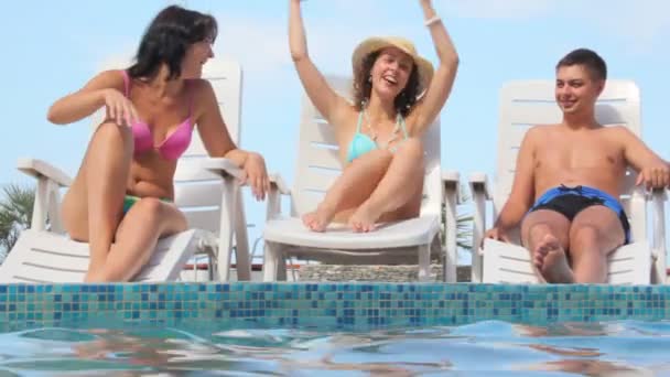 Mulher acenando mãos senta-se na cadeira de praia perto da piscina de água, amigos se diverte — Vídeo de Stock