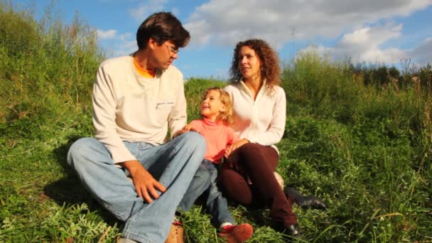 Familia feliz sentada en la hierba — Vídeo de stock