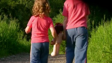 kız ve erkek bebek tutan ve parkta yürüyor