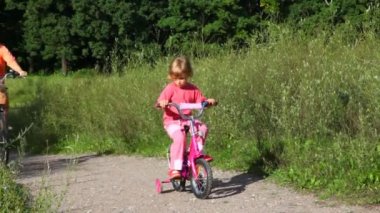 Kız bisiklet üzerinde oturur, kadın rides parkta geçmesi