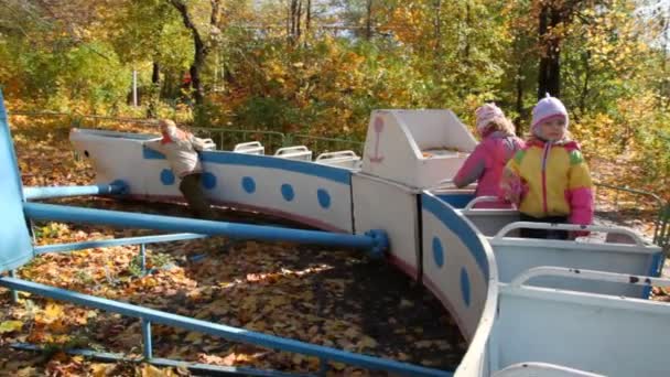 Boy pushing on carousel with girls on playground — Stock Video