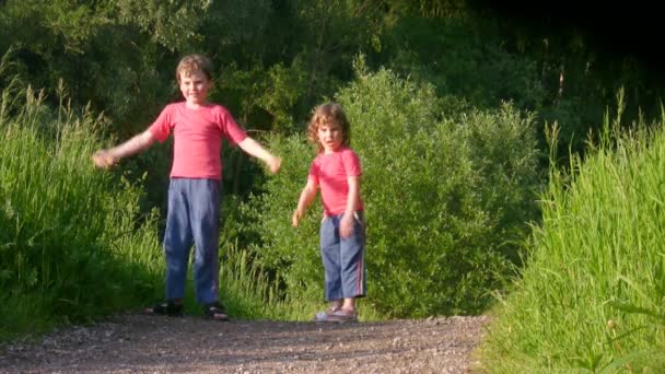 Mädchen und Junge turnen im Sommerwald — Stockvideo