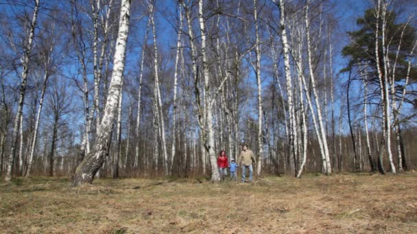 Famille de trois avec petit fils vient à la caméra dans la forêt de printemps 