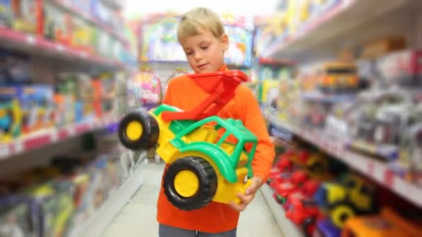 Boy examines toy excavator in store — Stock Video