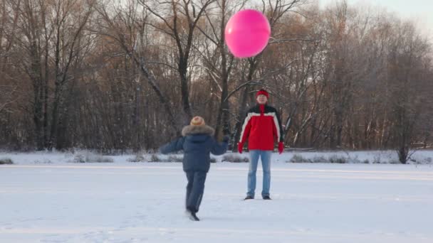 Father and son plays with air-balloon in snowfield — Stock Video