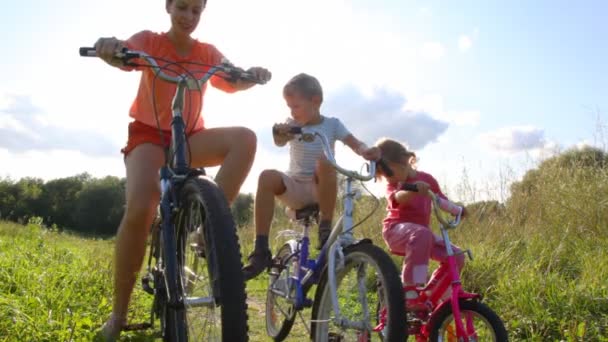 Family of three with bicycles in field — Stock Video