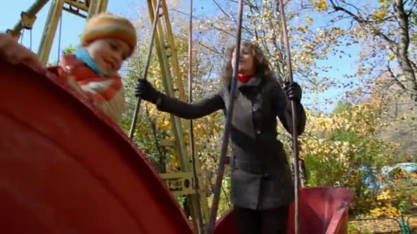 Vrouw en jongen balanceert op swing boot — Stockvideo