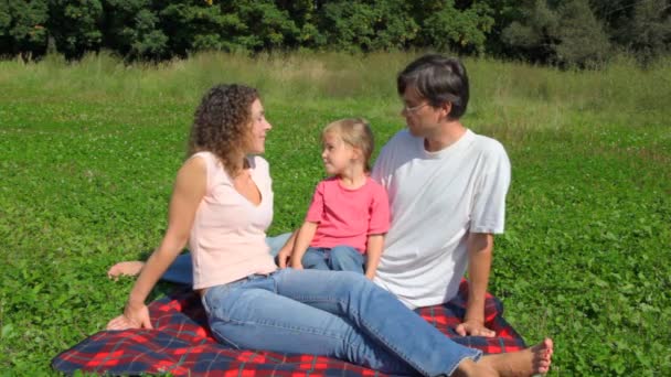 Gelukkige familie zit op veld in zomer park — Stockvideo