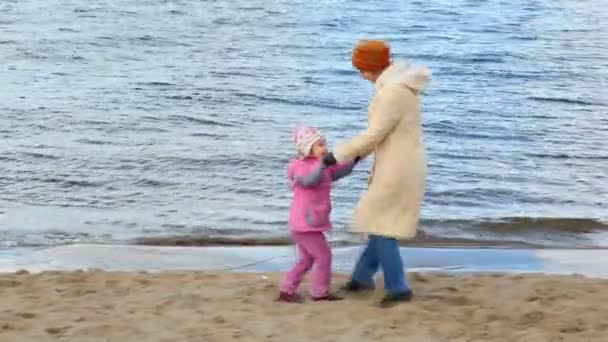 Mujer y niña bailan en la playa de arena — Vídeo de stock