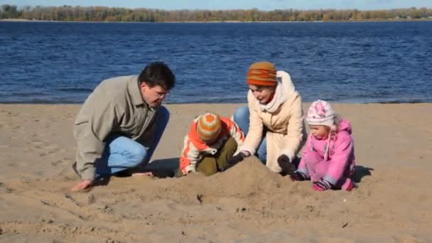 Family constructing sand buildings on beach — Stock Video