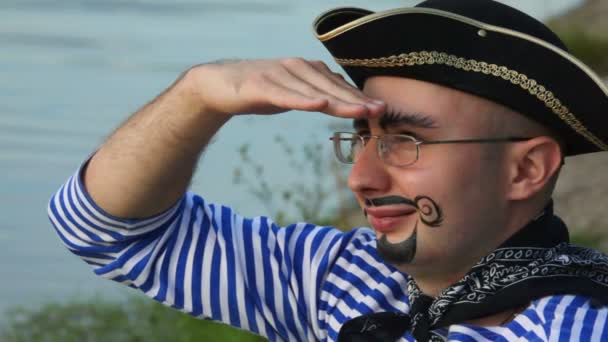 Man with drawed beard and moustaches in pirate costume and hat looks at sea — Stock Video