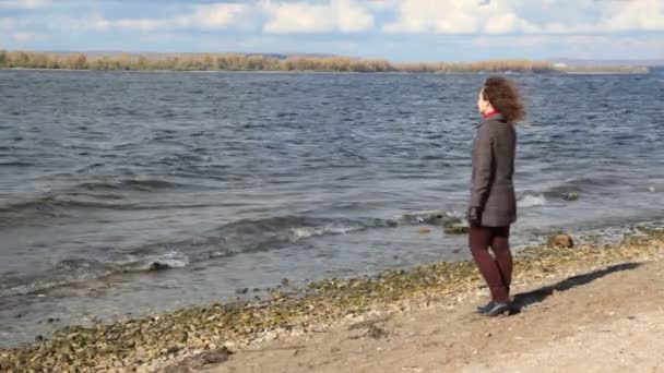 Vrouw staat op de bank en kijkt naar de rivier — Stockvideo