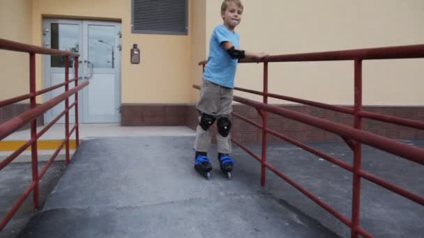 Boy in elstringed pads and knee-pads rollerblading near estate — Stock Video