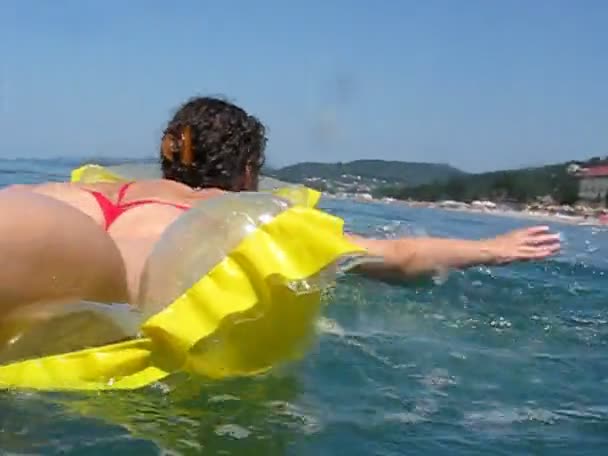 Woman lies on inflatable mattress and oars in sea — Stock Video