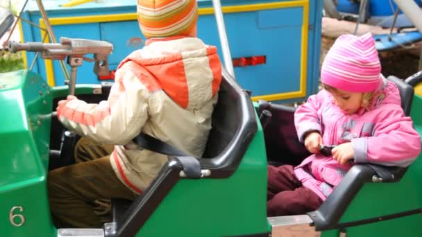 Niño y niña se sienta en dodgem en el parque de atracciones de la ciudad — Vídeos de Stock