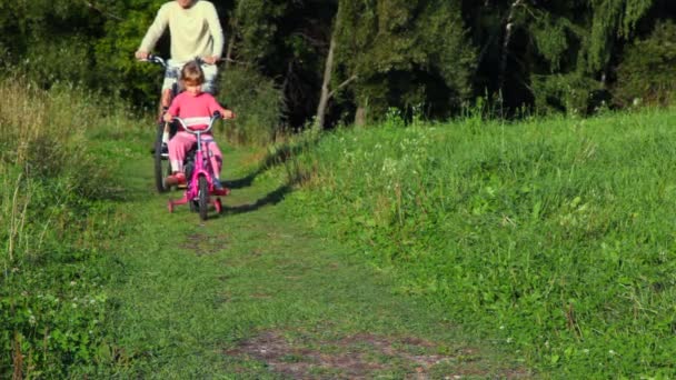 Man and girl riding bicycles in park — Stock Video