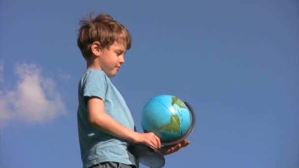 Boy standing rotates terrestrial globe — Stock Video