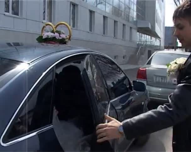 Groom opens cars door and gives hand to his bride — Stock Video