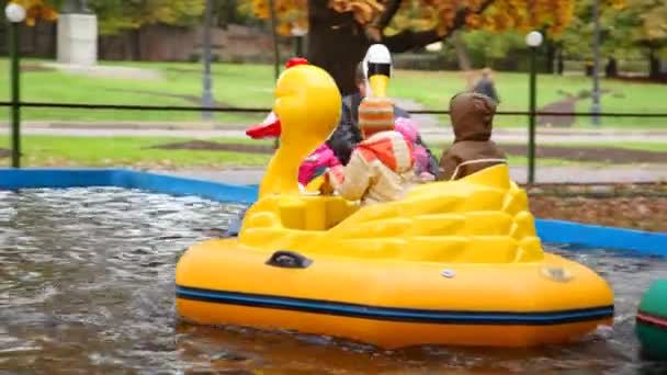 Sits in toy ducks on water in amusement park — Stock Video