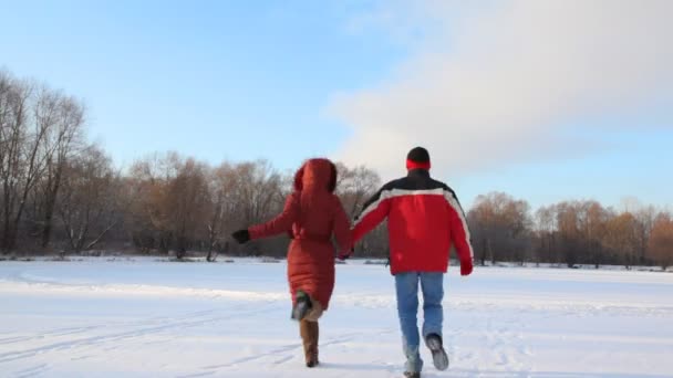 Мужчина и женщина бегают по снежному полю — стоковое видео