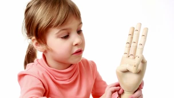 Girl flexes fingers of wooden model of human hand and brings it closer to screen — Stock Video