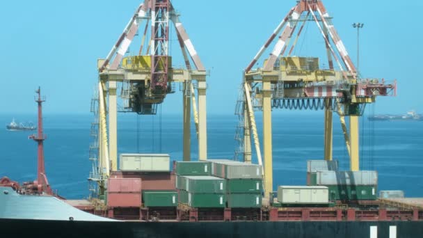 Завантаження вантажів у порту проти моря, на якому плавають кораблі. Проміжок часу . — стокове відео