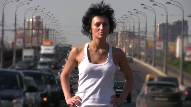 Girl stands on highway middle, sunny day in city — Stock Video