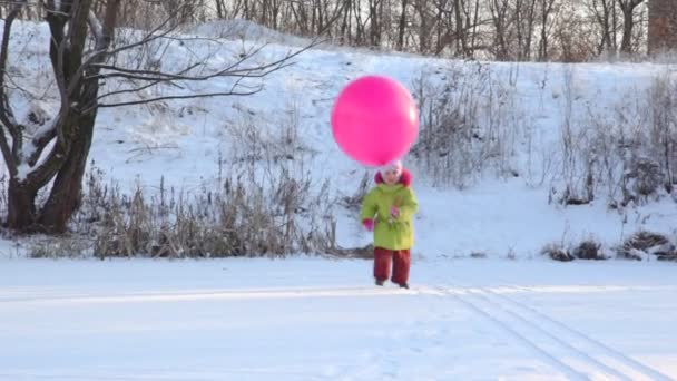Girl plays with air-balloon in snowfield — Stock Video